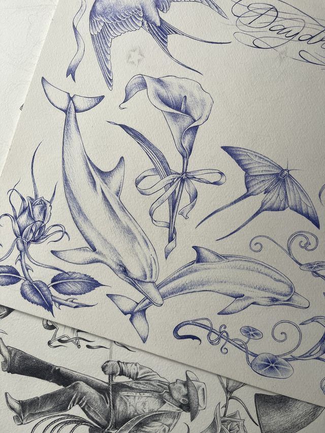 Blue ballpoint flash sheet — two dolphins, calla lilies with a ribbon, a flying fish and a swallow.