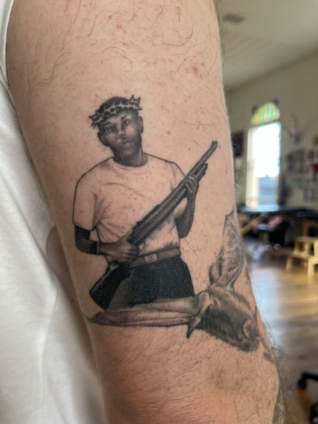 Realism portrait of a man wearing a crown of thorns and holding a rifle, on an upper arm.