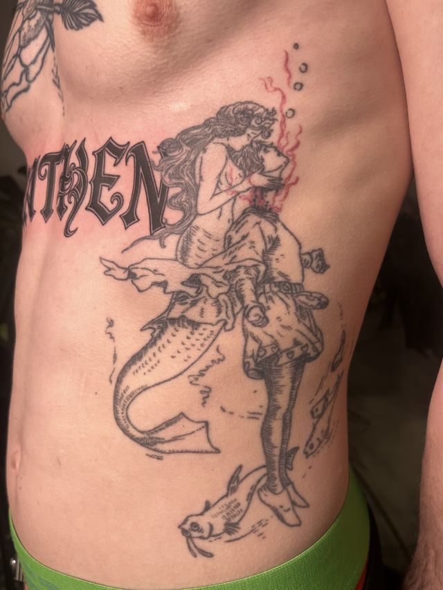 Illustrative mermaid and sailor embracing, across the ribs and side.