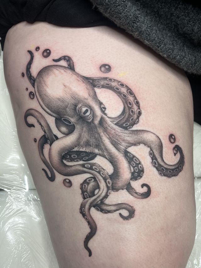 Black and grey octopus with curling tentacles and bubbles, on a thigh.