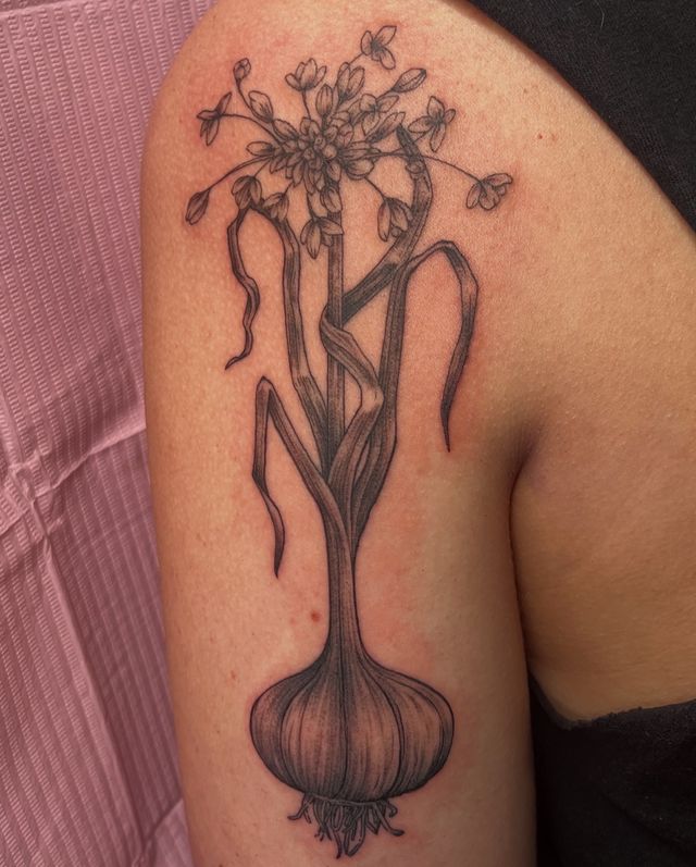 Fine line sprouting onion with a flowering stem, on an upper arm.