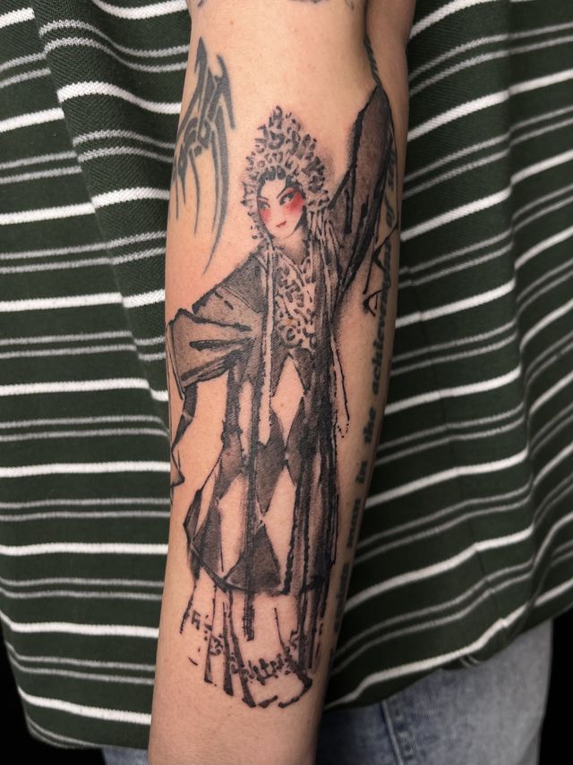 Illustrative figure in traditional Chinese opera costume and headdress, on a forearm.