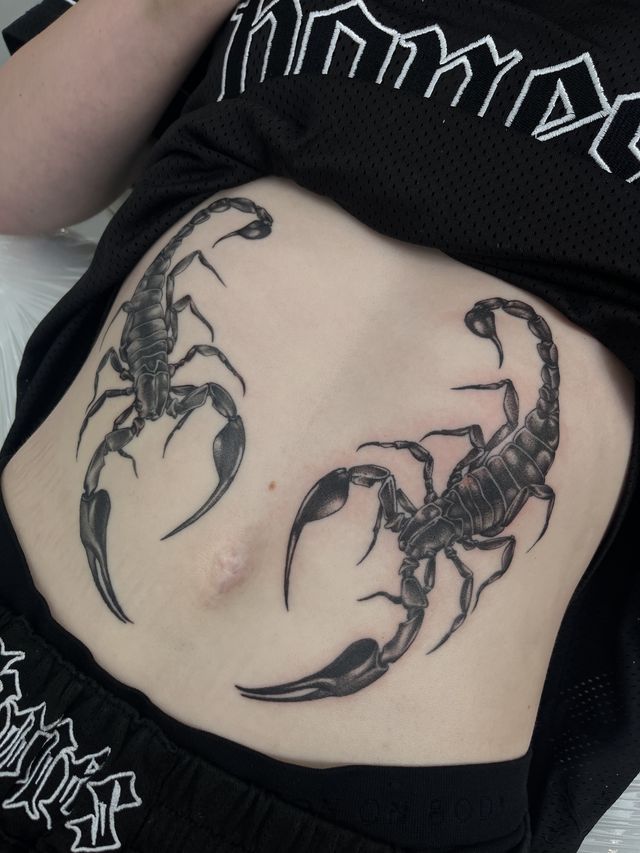Two mirrored black and grey scorpions across the stomach.