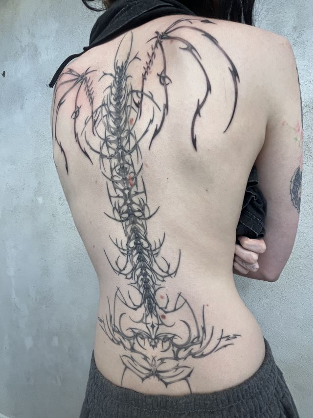 Fine line spine and pelvis motif with thorny growth running the length of the back.