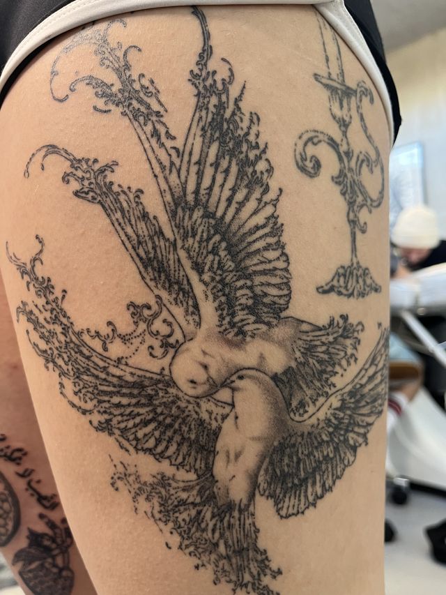Fine line winged horse rearing amid ornamental scrollwork, along a thigh.